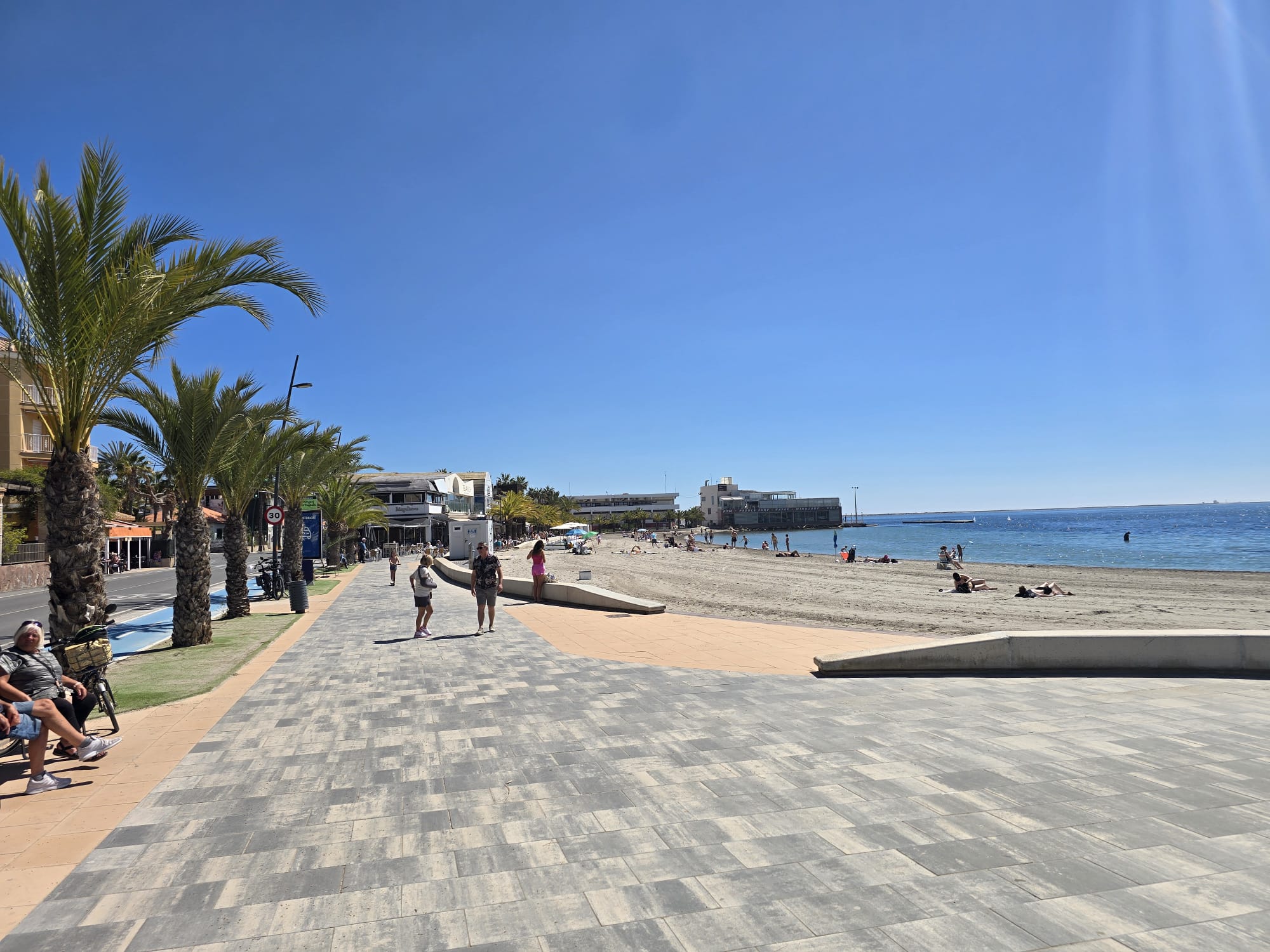 Promenáda s palmami vedúca pozdĺž pieskovej pláže